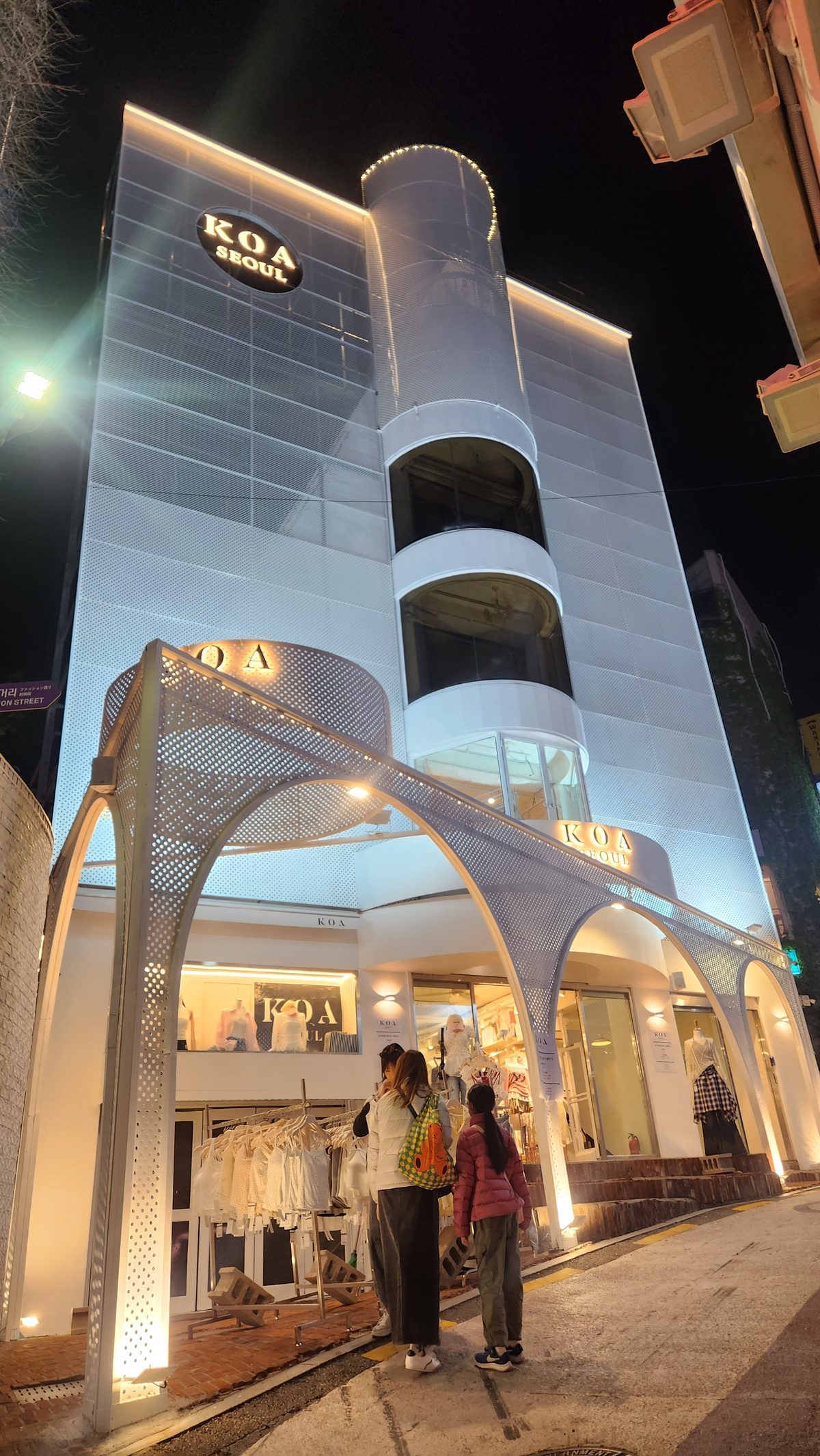 KOA Seoul — a white perforated-metal building lit at night, arches over the entrance